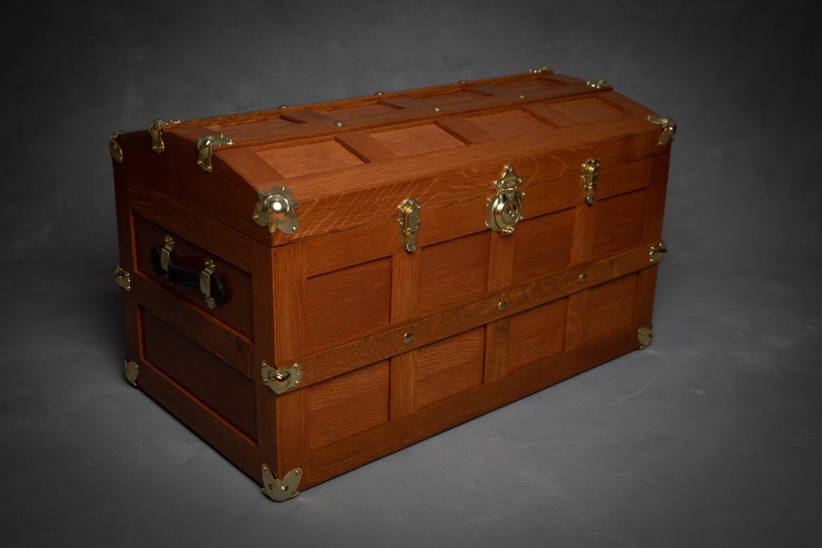 A wooden trunk with brass hardware on top of it.