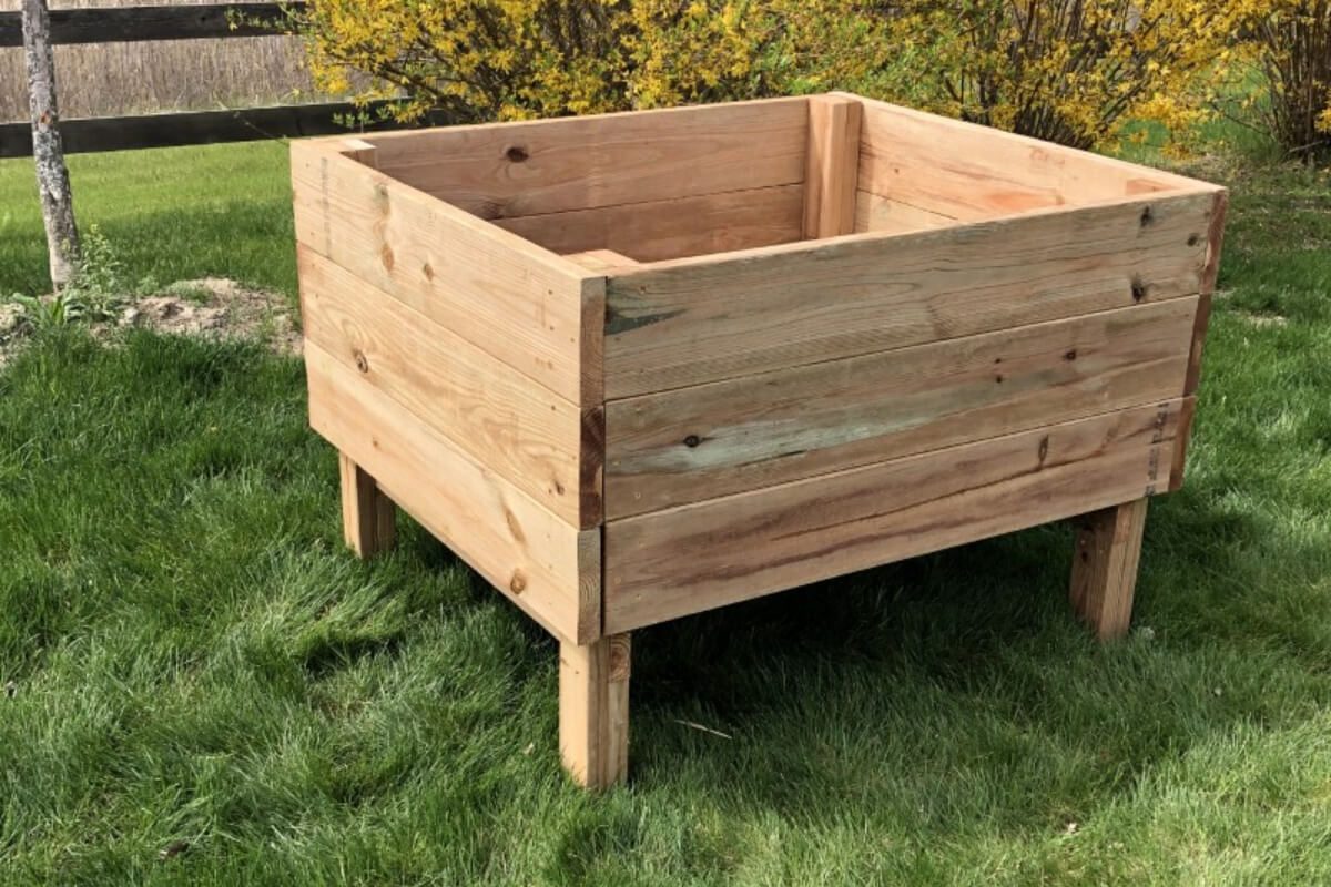 A wooden planter box sitting in the grass.