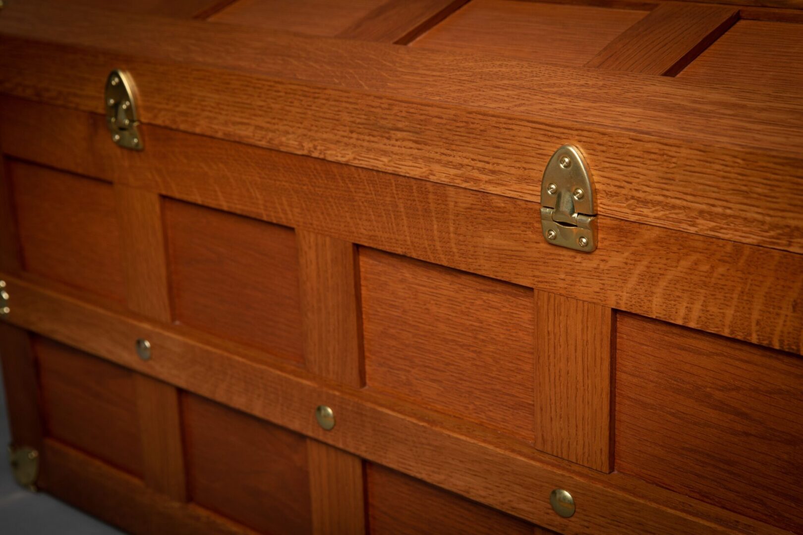 A close up of the wooden chest with brass hardware.