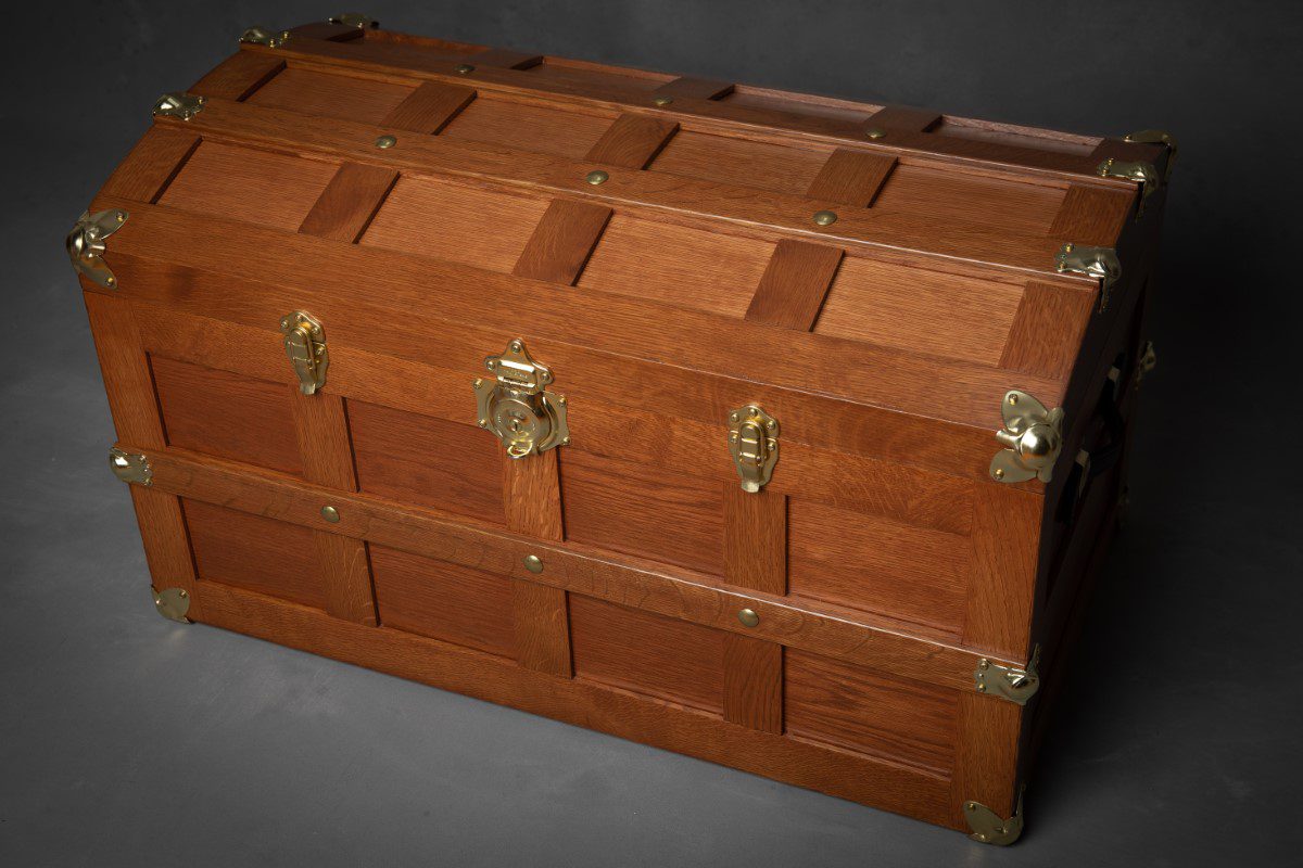 A wooden trunk with brass hardware and two handles.