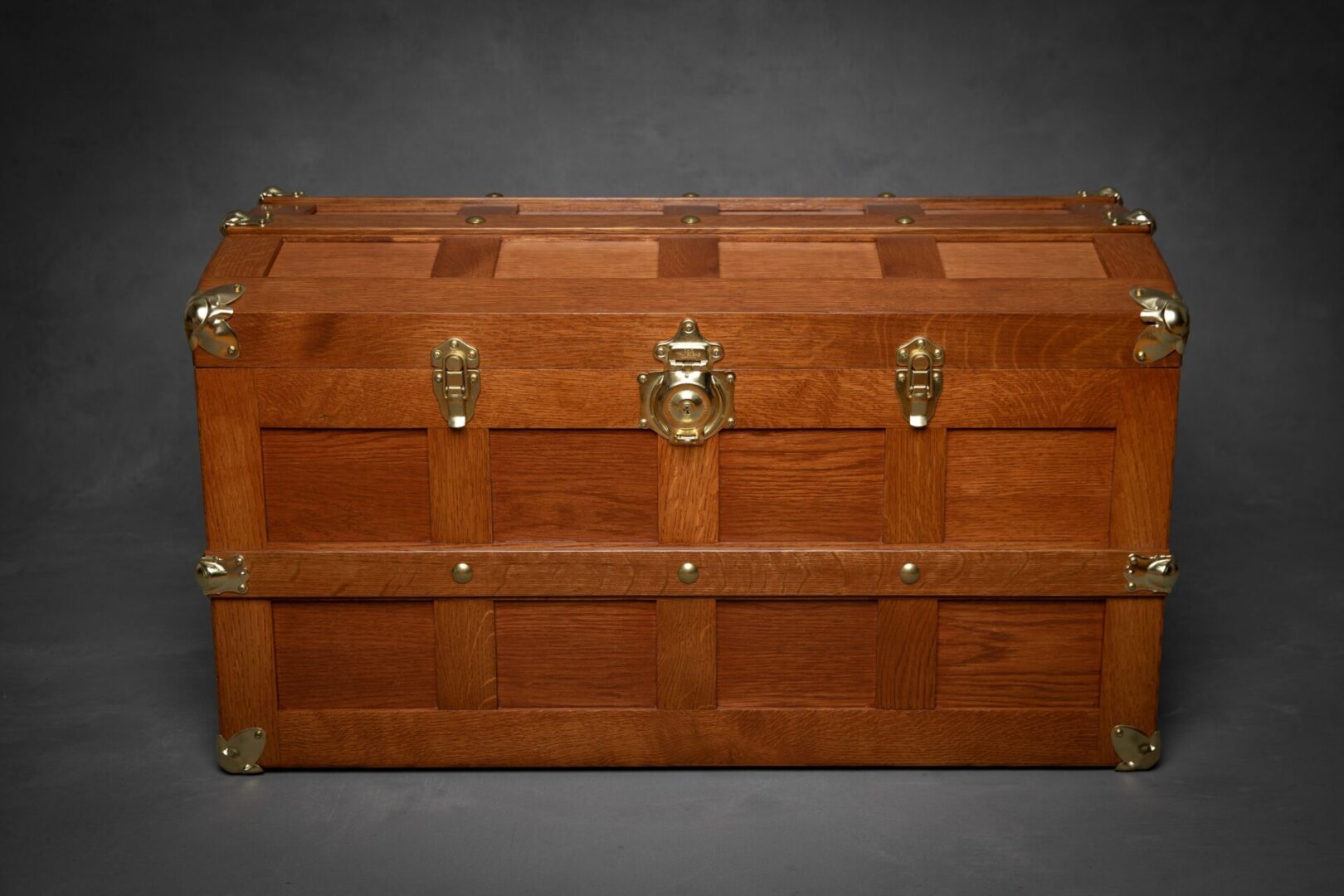 A wooden trunk with brass hardware on top of it.