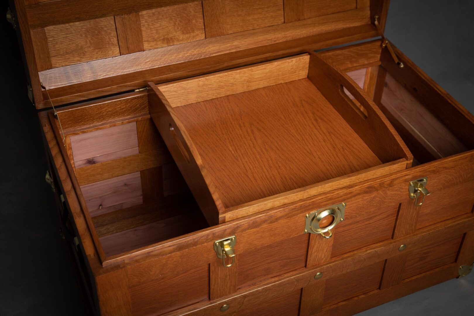 A wooden chest with two trays on top of it.