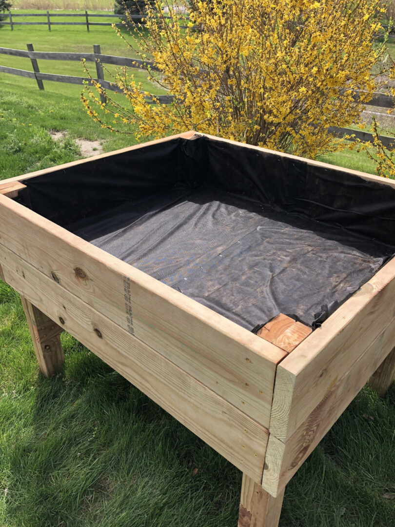 A wooden planter box with black tarp on top.