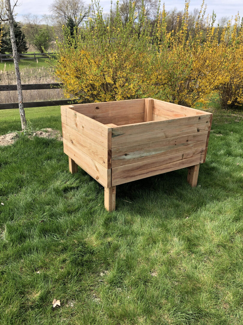 A wooden planter box sitting on top of grass.