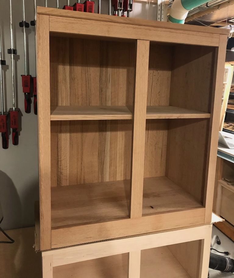 A wooden shelf with two shelves and one of the sides is open.