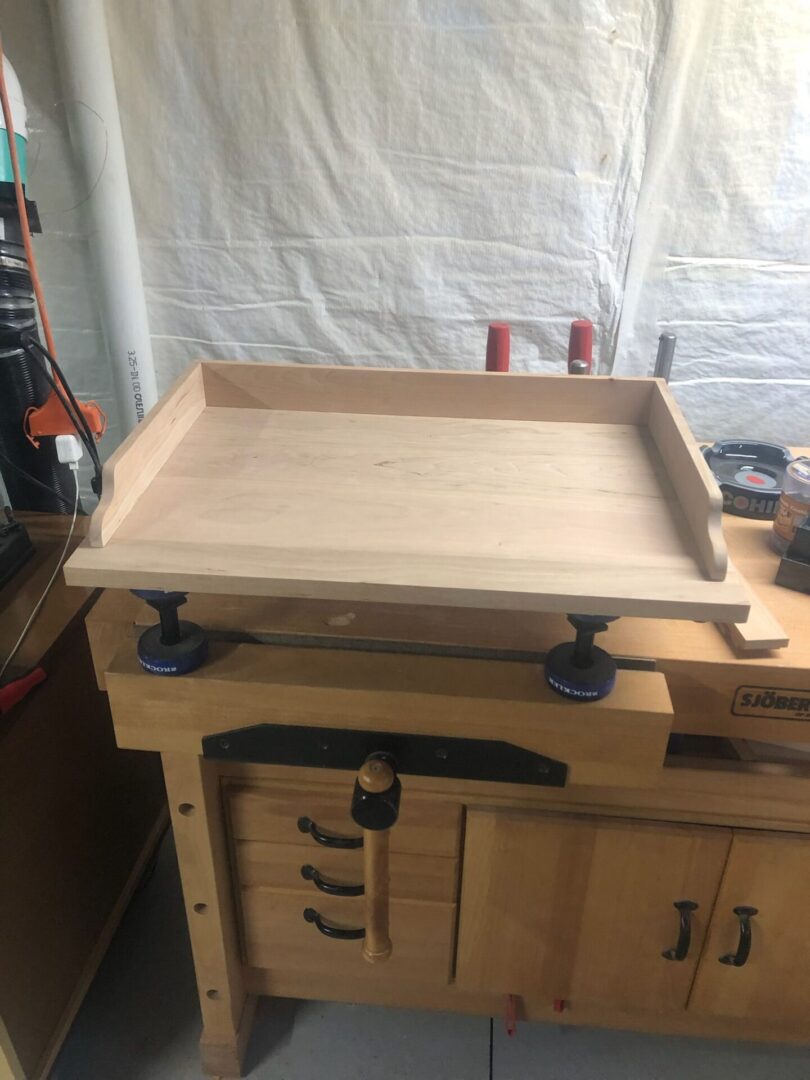 A wooden tray sitting on top of a workbench.